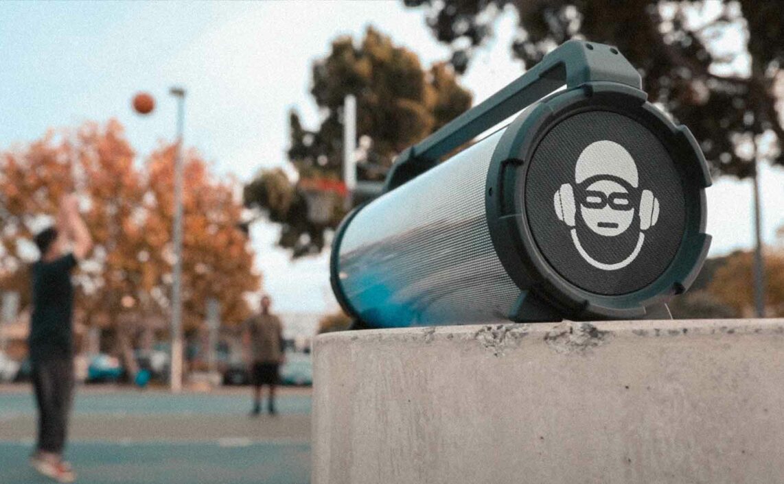 IDance Cyclone speaker in a park with people playing basketball on the back